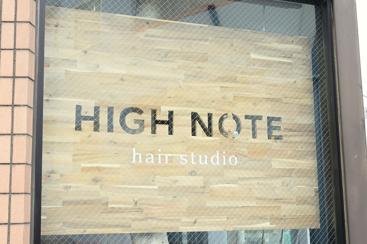 木板にステンシルされた「HIGH NOTE hair studio」の看板（目印）
